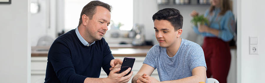Un padre le enseña a su hijo a usar el teléfono de forma responsable.