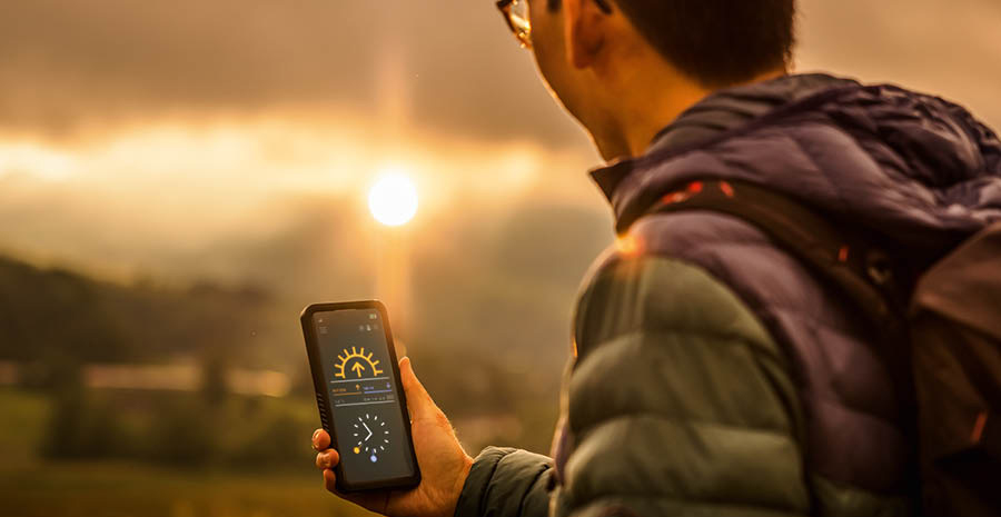 Un joven mira en su teléfono a qué hora se pone el sol.