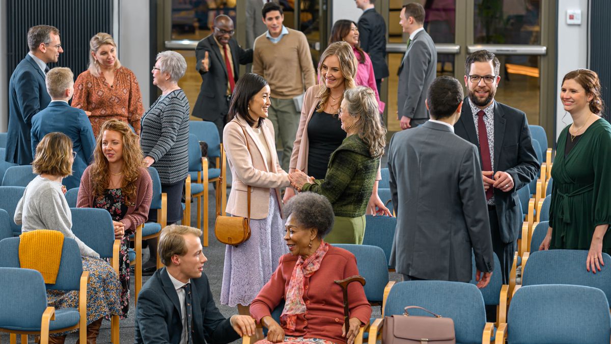 En un Salón del Reino de los testigos de Jehová, personas de diferentes edades y antecedentes se saludan con cariño y hablan unas con otras antes de la reunión.