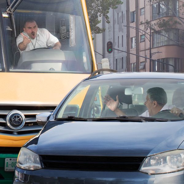 El conductor de un autobús le grita muy enojado a otro conductor que le cortó el paso en la carretera.