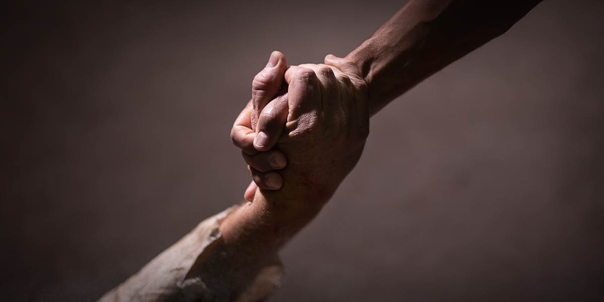 Una persona agarrando la mano de alguien para ayudarlo.