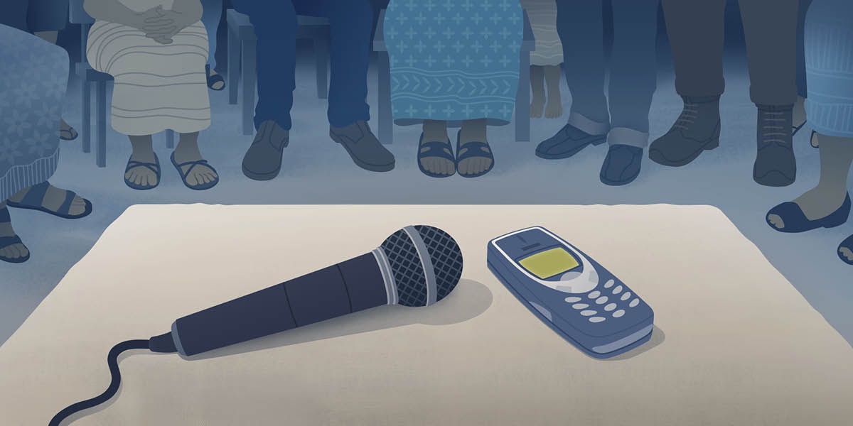 Un grupo de personas se reúne para estudiar la Biblia por teléfono. Hay un micrófono junto al teléfono para que todos puedan escuchar la lección.