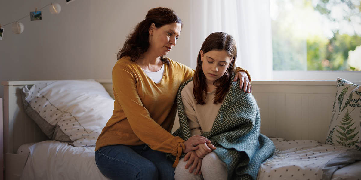 Una madre consolando a su hija, que está deprimida.
