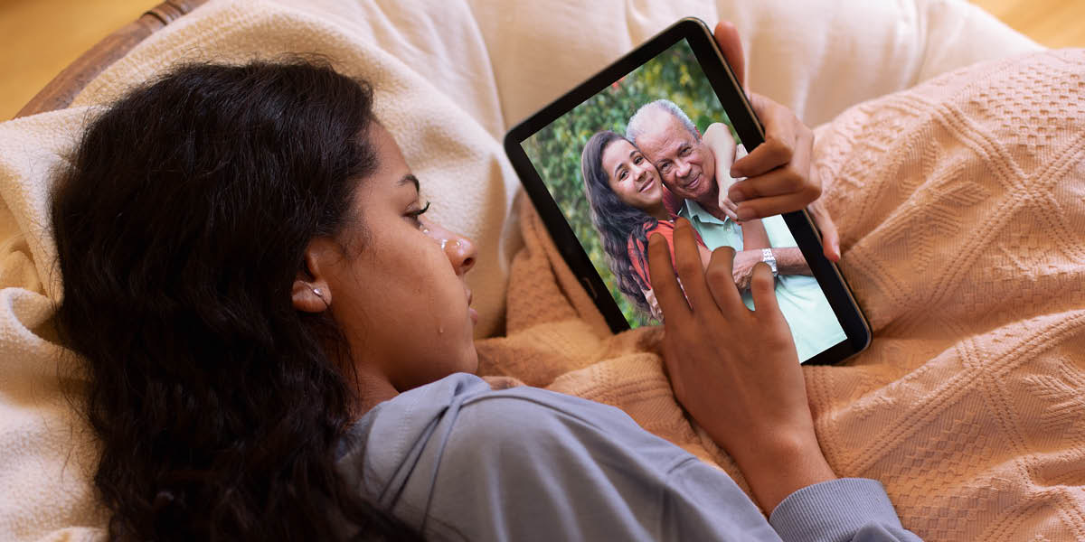 Una joven adolescente está en la cama llorando mientras mira una foto de ella con su abuelo.