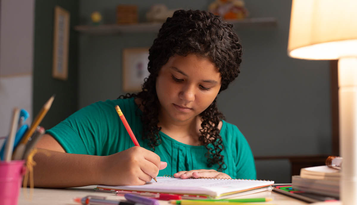 Una jovencita escribiendo en un cuaderno.