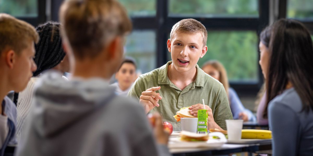 Un joven hablando con sus compañeros de escuela en el comedor.