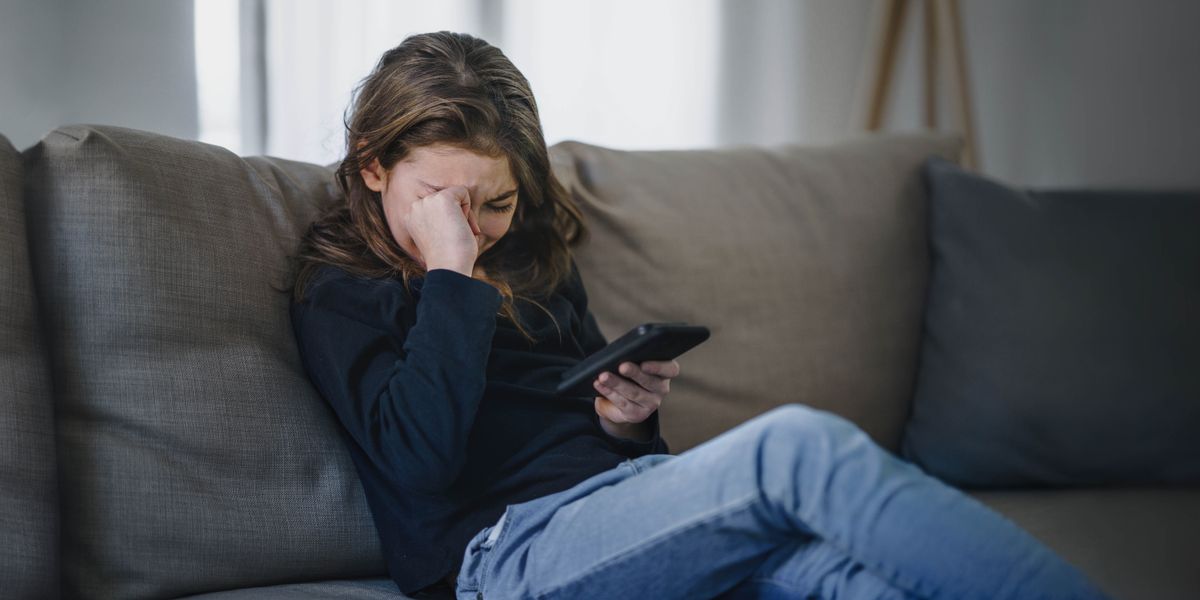 Una adolescente está llorando porque vio algo en su teléfono que la hizo sentir muy mal.