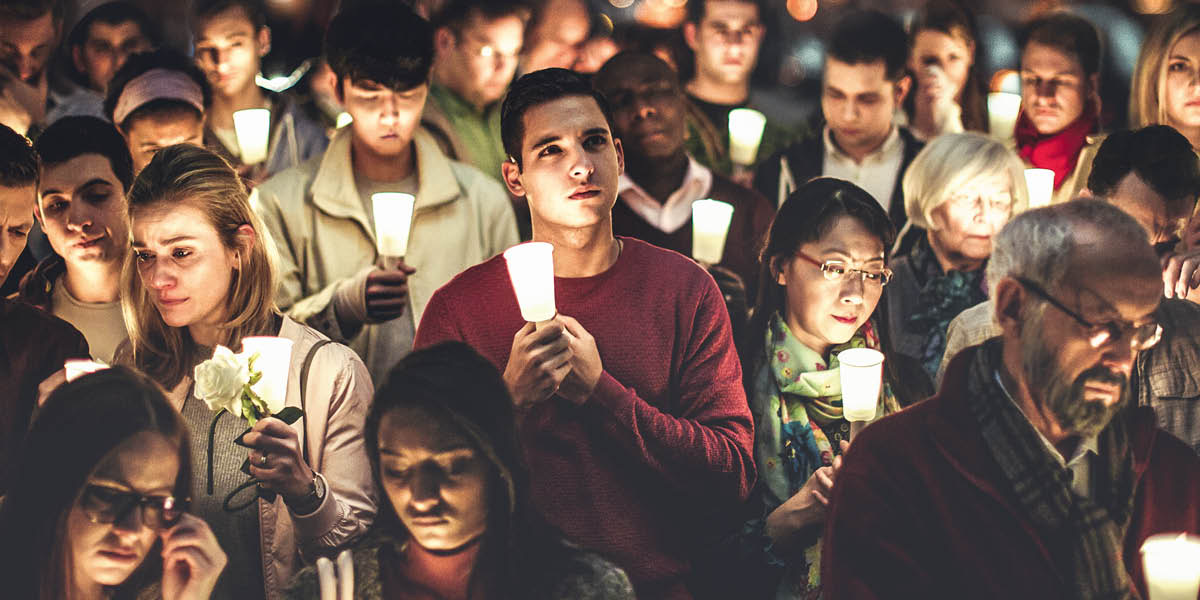 Unas personas sujetando velas en señal de duelo