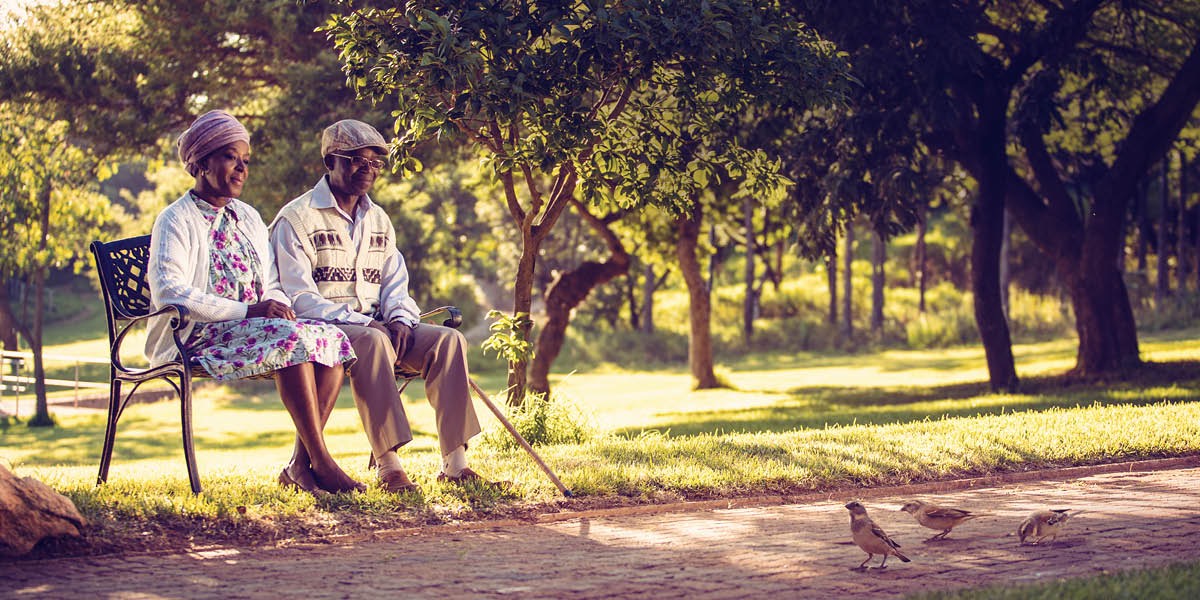 Un matrimonio sentado en el banco de un parque observando a los pájaros