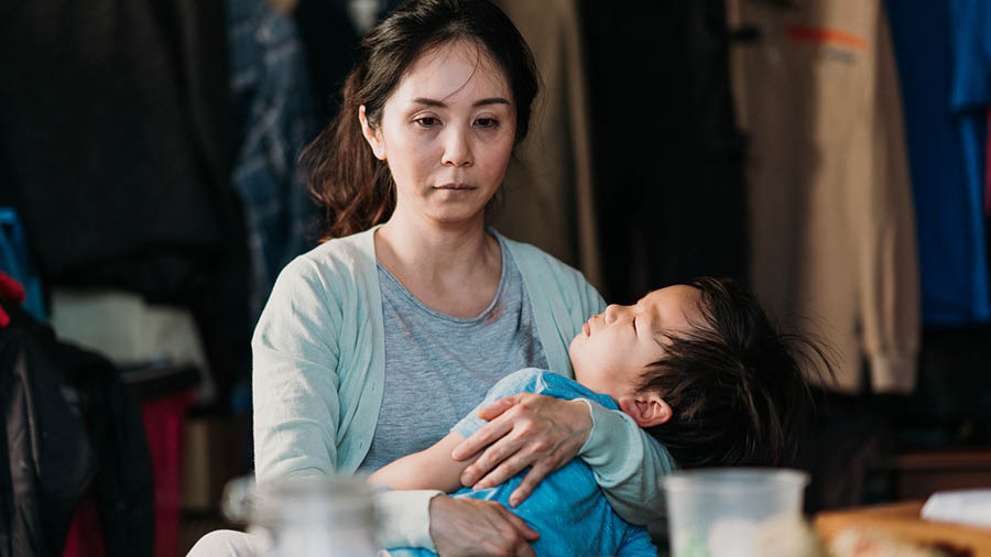 Al acabar el día, la misma mujer, triste y agotada, mece a su niño en sus brazos.