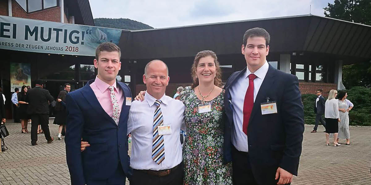 Artan, his wife Julinda, and their two sons at a convention of Jehovah’s Witnesses.