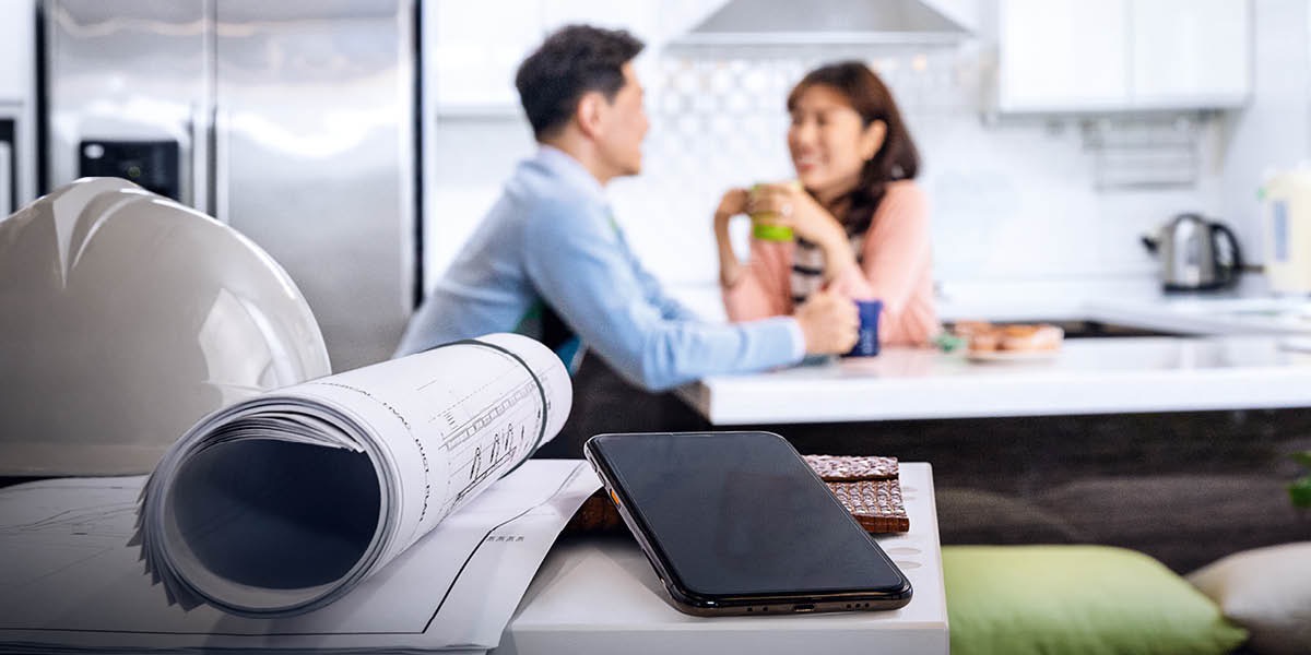 A husband and wife having coffee together at home in their kitchen. They have placed their work and cell phones out of reach.