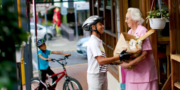 A teenage boy assisting an older woman with her bag of groceries