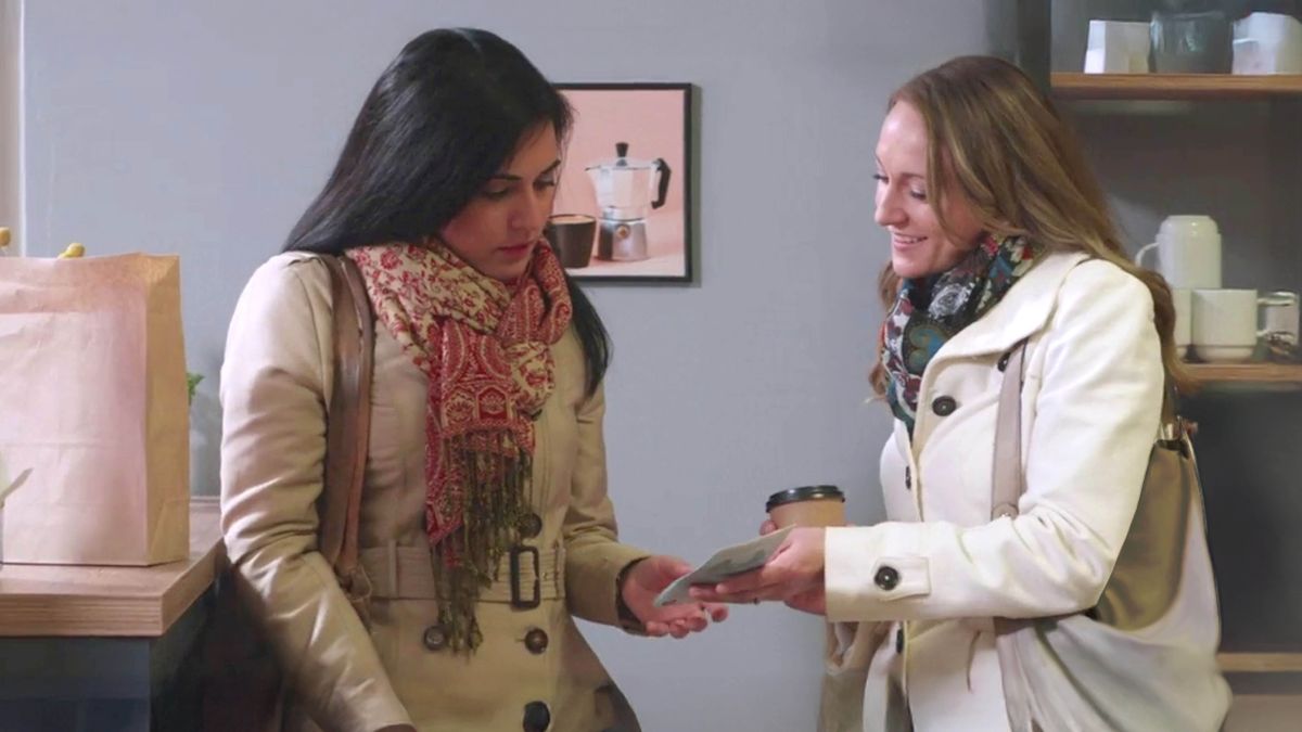 A scene from the video “Jehovah ‘Is Not Far Off.’” A sister giving a tract to a woman in a coffee shop.