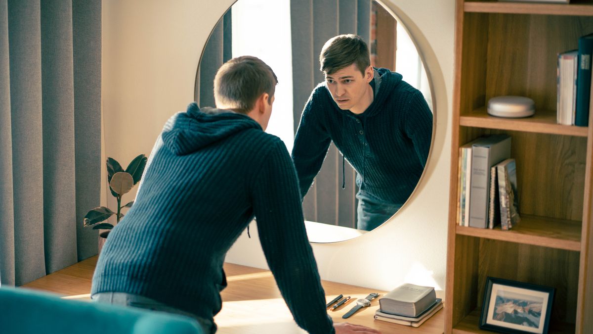 The young brother sadly gazes into a mirror as he reflects on his weaknesses.