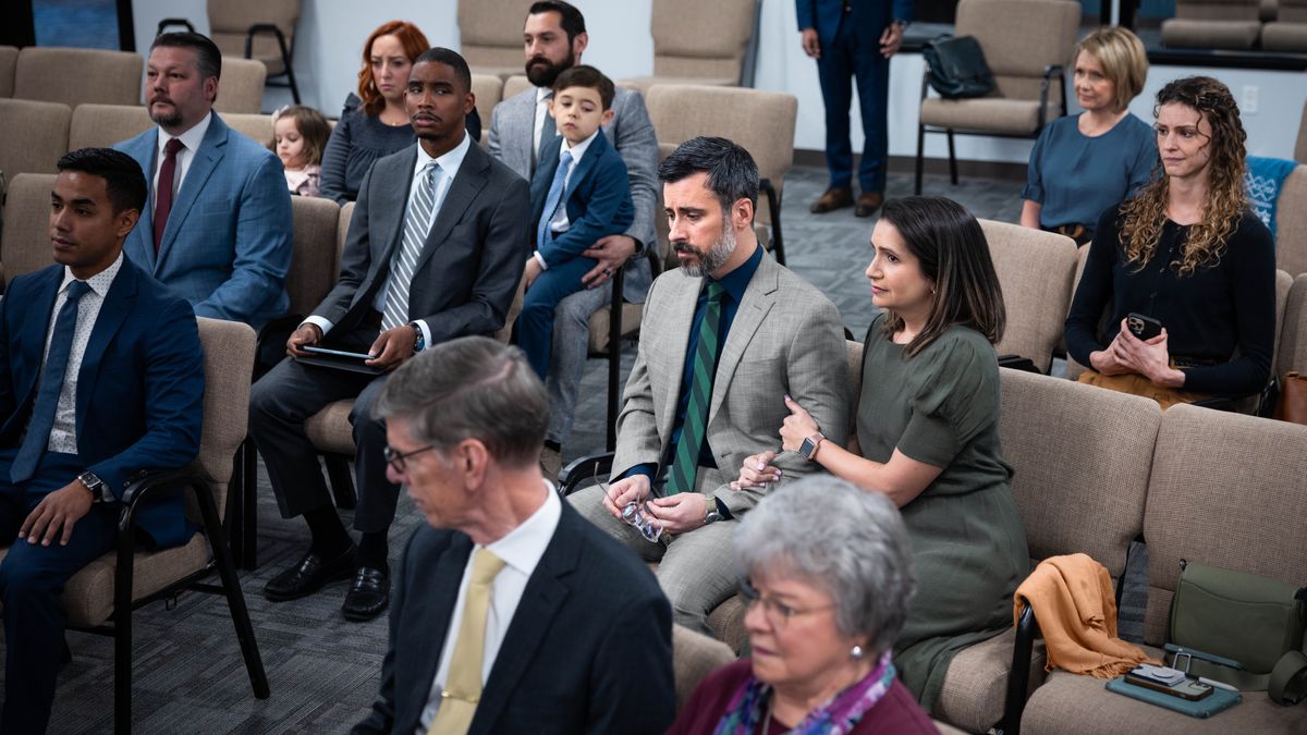 The brother and his wife sadly listen to an announcement at the Kingdom Hall.