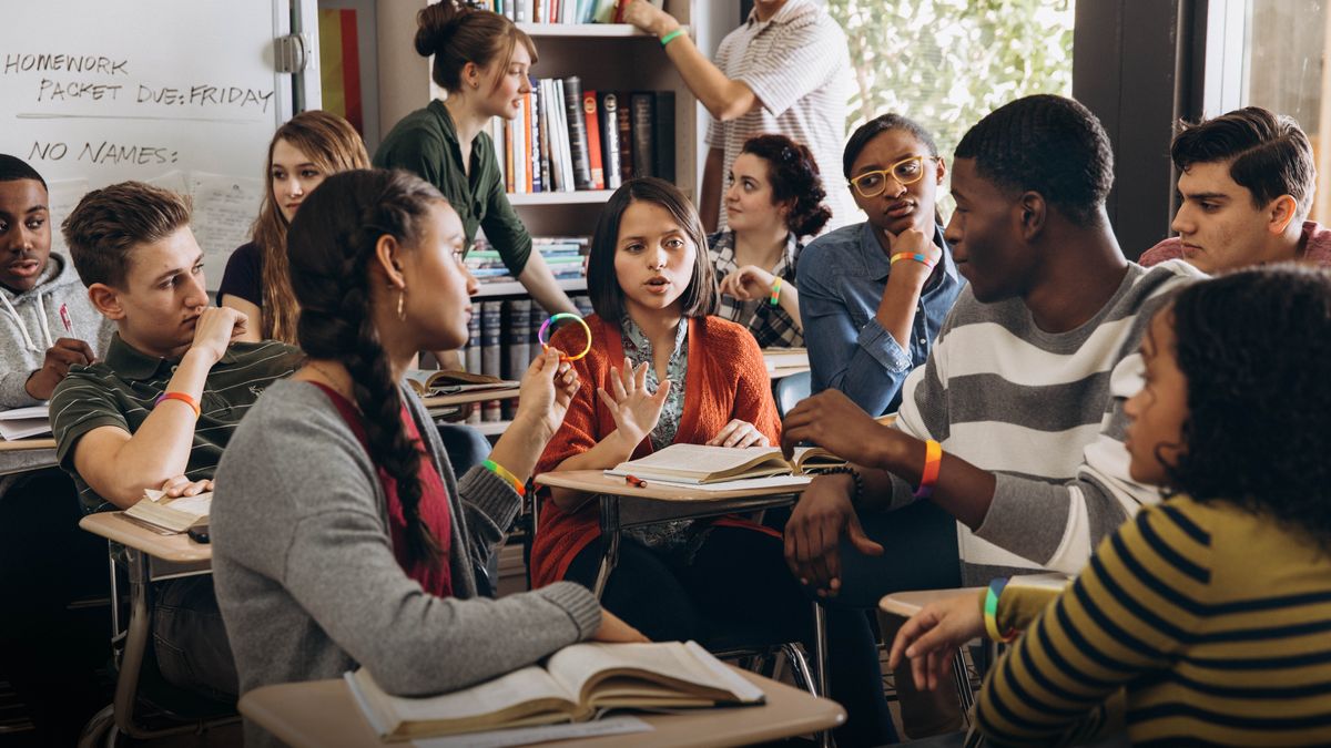 Later, in the classroom, the sister’s classmates urging her to wear a rainbow bracelet. She politely refuses while her classmates look at her in disbelief.