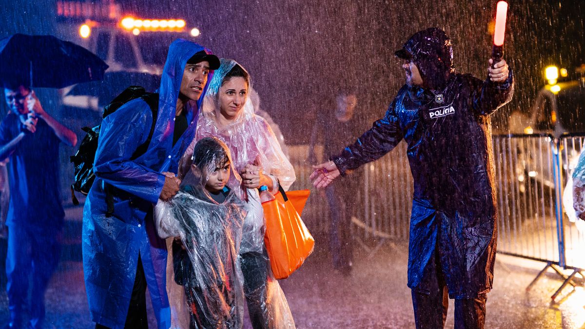 Un hermano con su mujer y su hija caminan bajo una fuerte tormenta. Siguen con calma las instrucciones de un policía que los dirige a un lugar seguro.