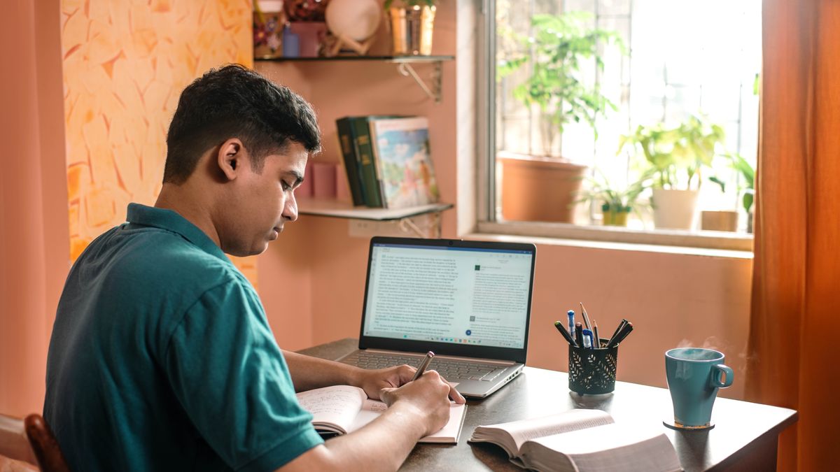 Un hermano hace anotaciones mientras estudia la Biblia. Usa la aplicación JW Library en su computadora y una biblia impresa.