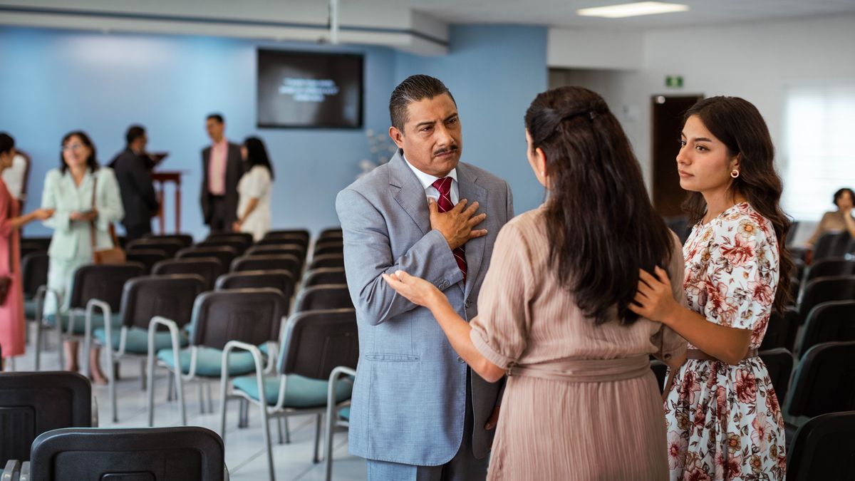 En el Salón del Reino, un anciano escucha con empatía a dos hermanas que le están contando un problema.