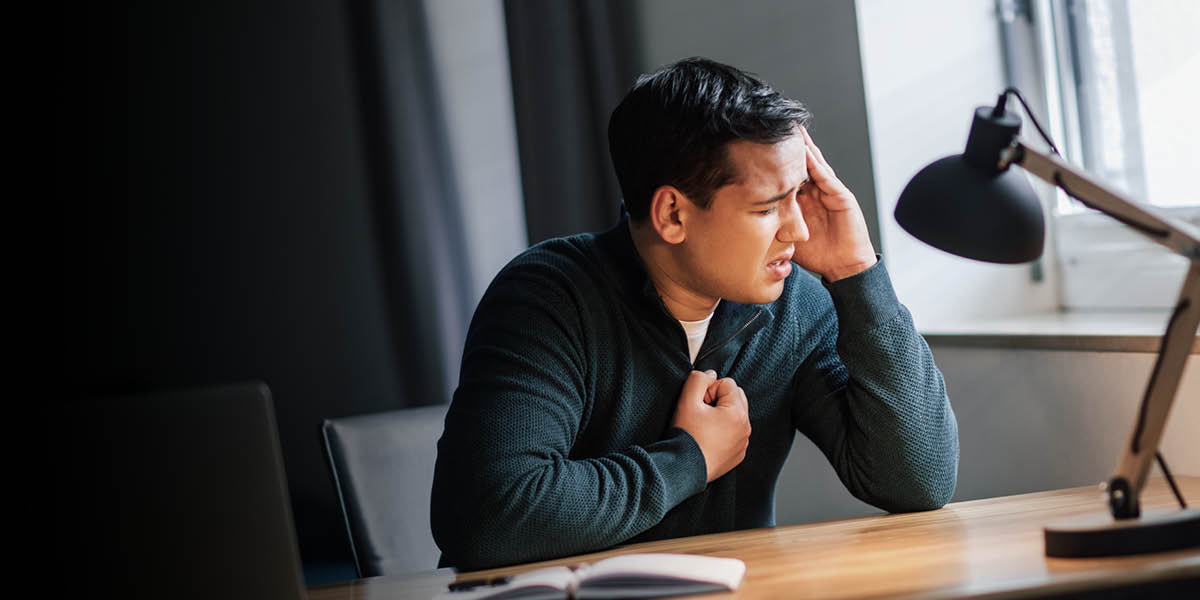 Ahdistunut nuori mies pitelee kättään rintaansa vasten ja rukoilee.