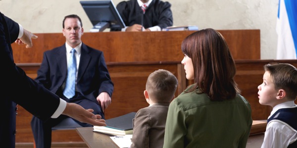 Dans un tribunal, un homme est sur le banc des accusés ; sa famille assiste au procès