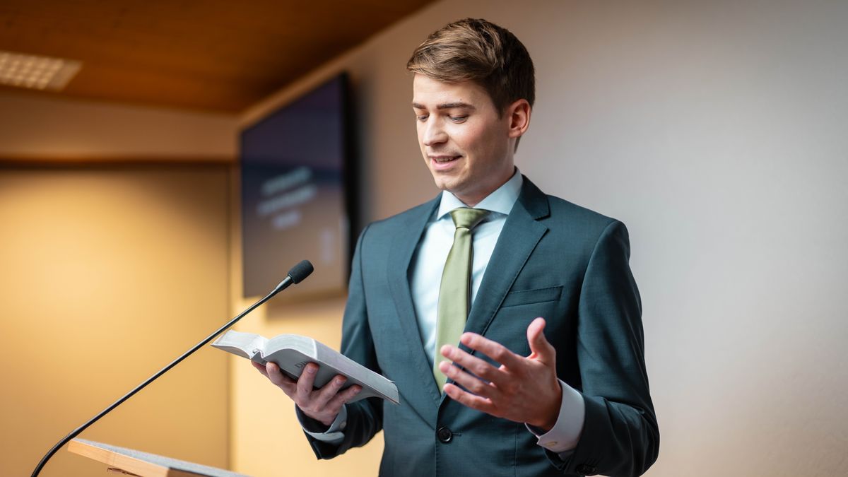 Lors d’une réunion de l’assemblée, le jeune frère lit la Bible sur l’estrade.