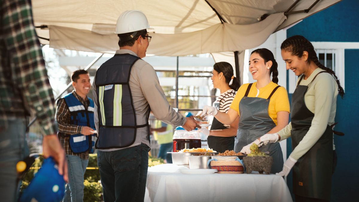  Sur un chantier de construction, trois sœurs souriantes servent de la nourriture à des frères.
