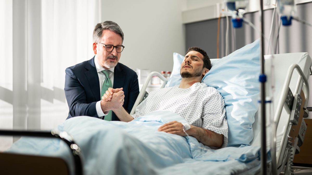 À l’hôpital, un frère prie au chevet d’un autre qui est couvert de bleus.