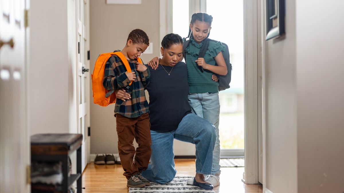 Agenouillée, une mère prie avec ses deux enfants avant qu’ils partent à l’école.