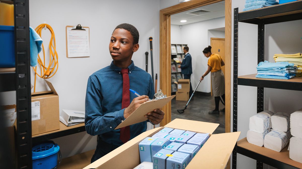 Dans une salle du Royaume, un frère adolescent fait l’inventaire des produits d’entretien. Dans le hall d’entrée, un frère remet des publications à la disposition des frères et sœurs, et une sœur passe l’aspirateur.
