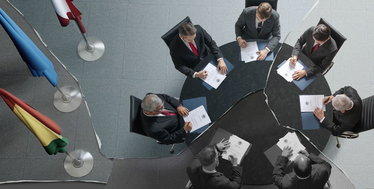 Une photographie déchirée montre un groupe de dirigeants politiques assis autour d’une table. Chacun signe un exemplaire du même document.