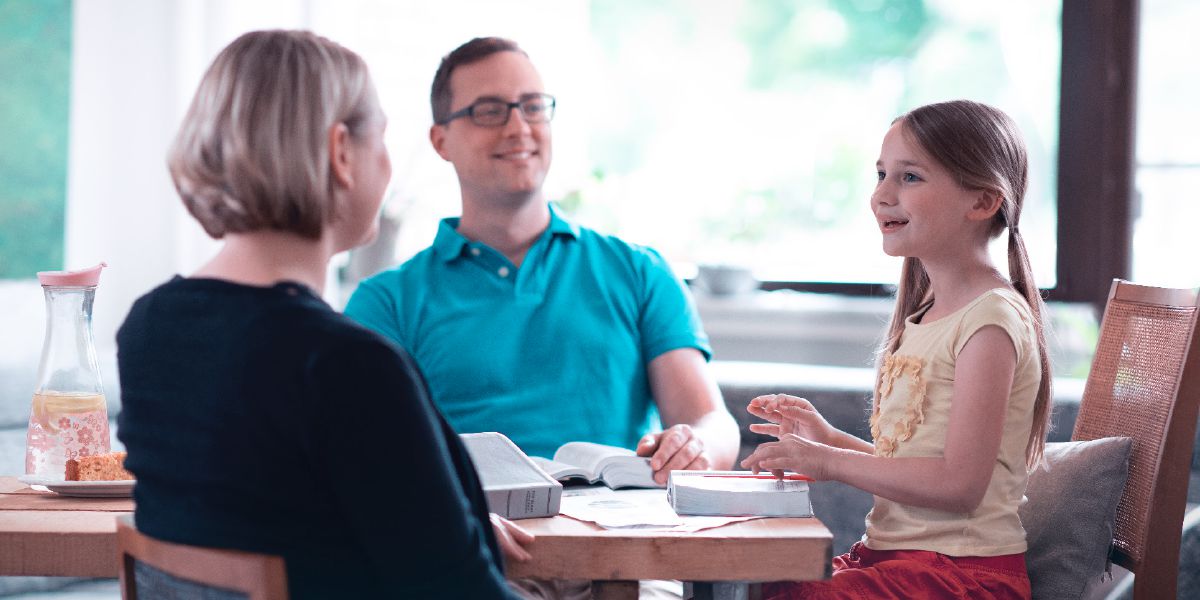 Unha nena sorrí mentres seus pais lle aprenden da Biblia