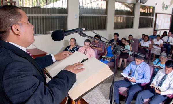 Julio Corio dando unha conferencia nunha congregación das testemuñas de Xehová coa axuda dunha Biblia en braille.