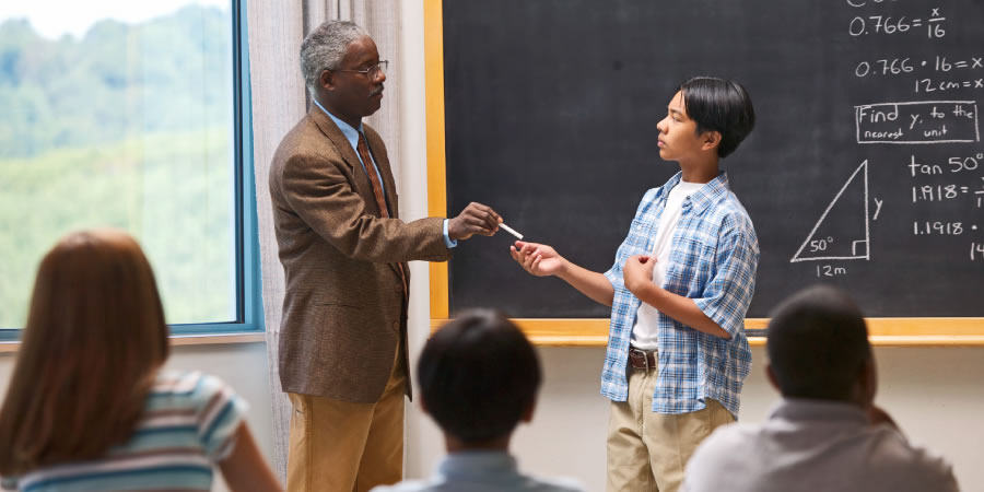 Lehrer lässt einen Schüler, der glaubt, es besser zu wissen, vor der Klasse eine schwierige Aufgabe lösen
