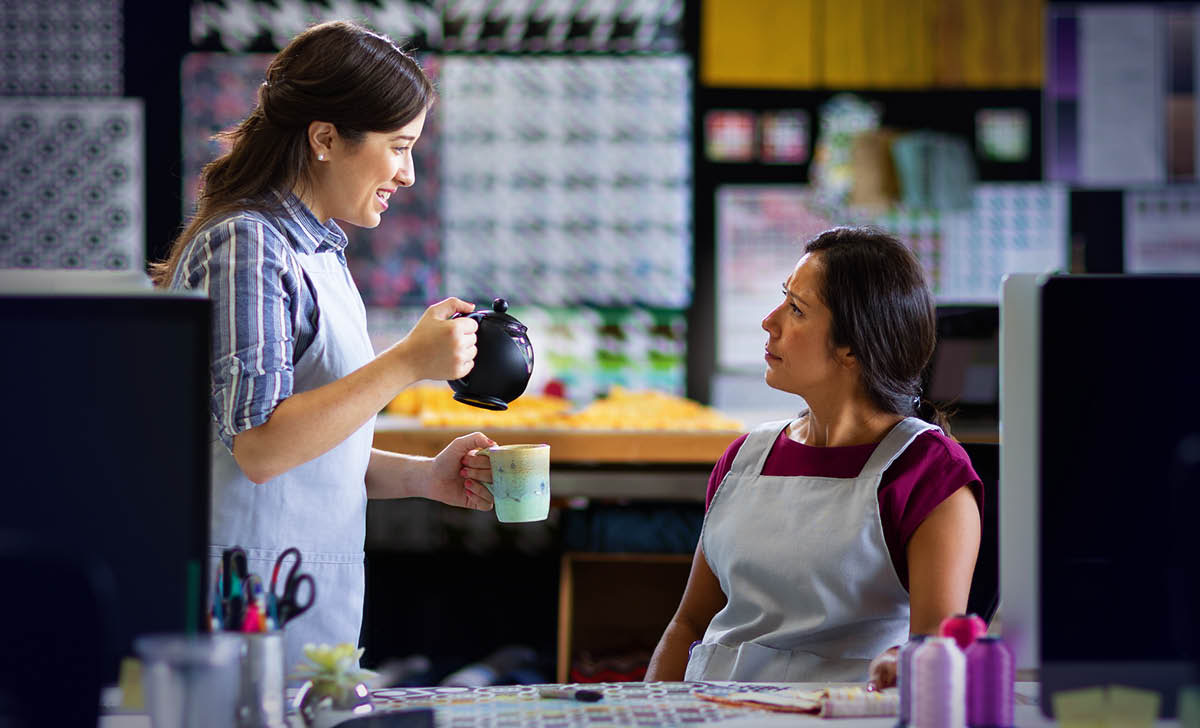 Die gleiche Frau bietet ihrer überraschten Kollegin freundlich eine Tasse Tee an.