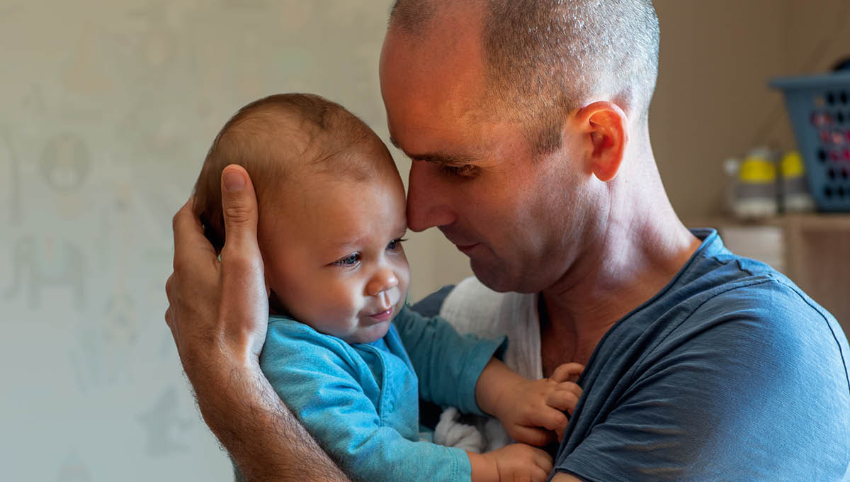 Ein Vater hält sein Baby liebevoll im Arm.