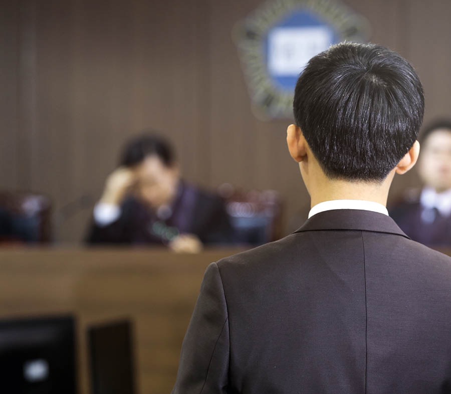Bildcollage: Situationen, in denen wir mutig sein können. 1. Im Klassenzimmer steht ein Junge ruhig da, während die anderen die Fahne grüßen. 2. Ein Bruder steht vor Gericht. 3. Ein junger Bruder bietet im Dienst von Haus zu Haus ein Traktat an und wird dabei von einem Polizisten beobachtet.