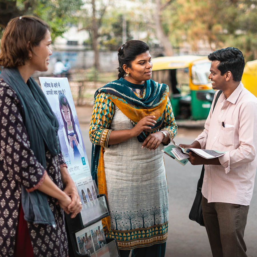 Dos hermanas predicando con un carrito y hablando con un hombre en la India.