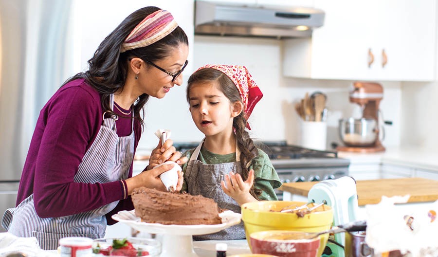 Una madre ayudando a su hija, que está triste porque le ha salido mal el bizcocho