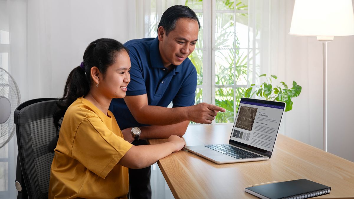 Un padre y su hija adolescente mirando en una computadora la página web de un museo.