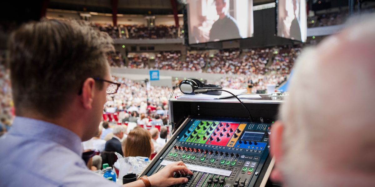 Peteĩ ermáno orregulaʼi pe volúmen, upe aja umi oĩva pe aty guasúpe ohecha peteĩ vidéo umi pantálla higántepe.