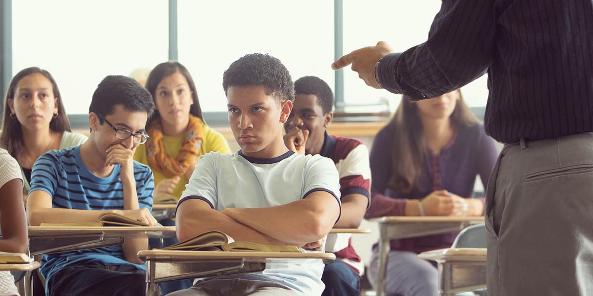 תלמיד יושב בכיתה,‏ והמורה שלו נוזף בו.‏