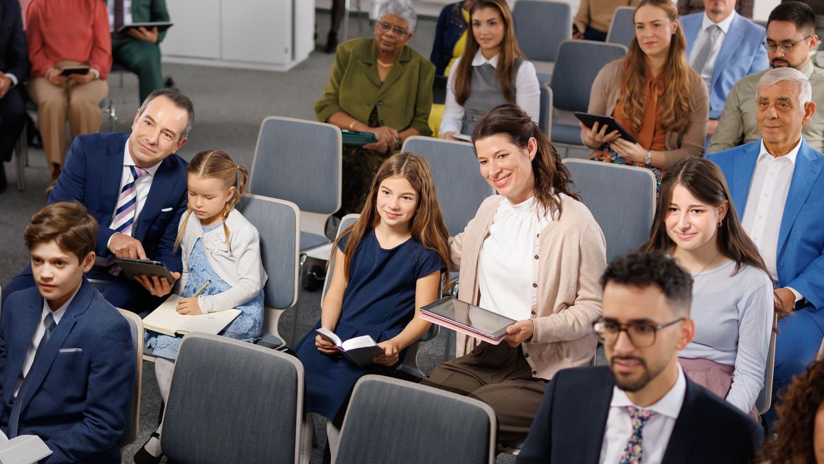 Olda an younga braddahs an sistahs pay attention to da meeting in da Kingdom Hall.