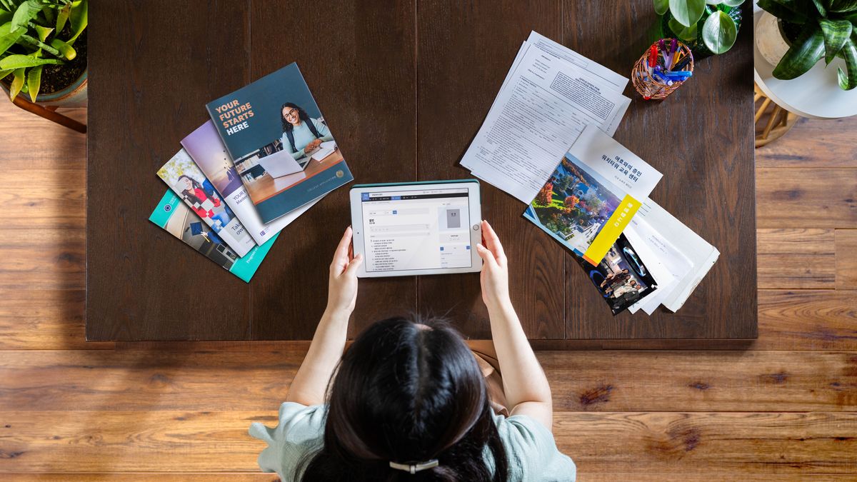 One young sistah using one tablet fo figga out wat kine goals she like make. On da left side, get brochures about going moa skool. On da right side, get one app fo do moa fo Jehovah an info about Bethel.