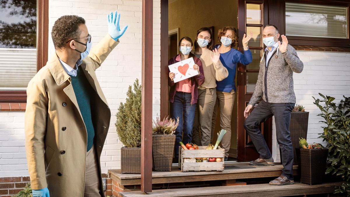 One braddah dropping off food to one ohana. All of dem waving to each odda an wearing masks.