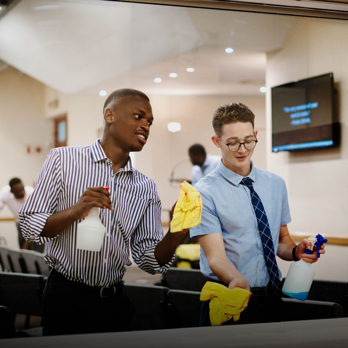 Two braddahs cleaning one window at da Kingdom Hall.