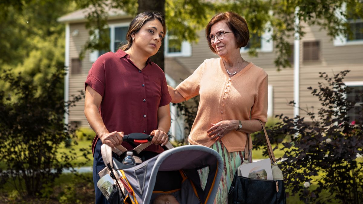 In field service, one sistah put her arm aroun anodda sistah who stay sad an pushing her bebe in one stroller.