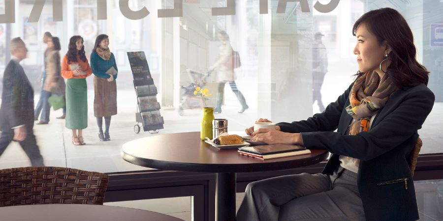 Մի կին նայում է համեստ հագուկապ ունեցող երկու Վկաներին, որոնք կանգնած են ցուցատախտակի մոտ