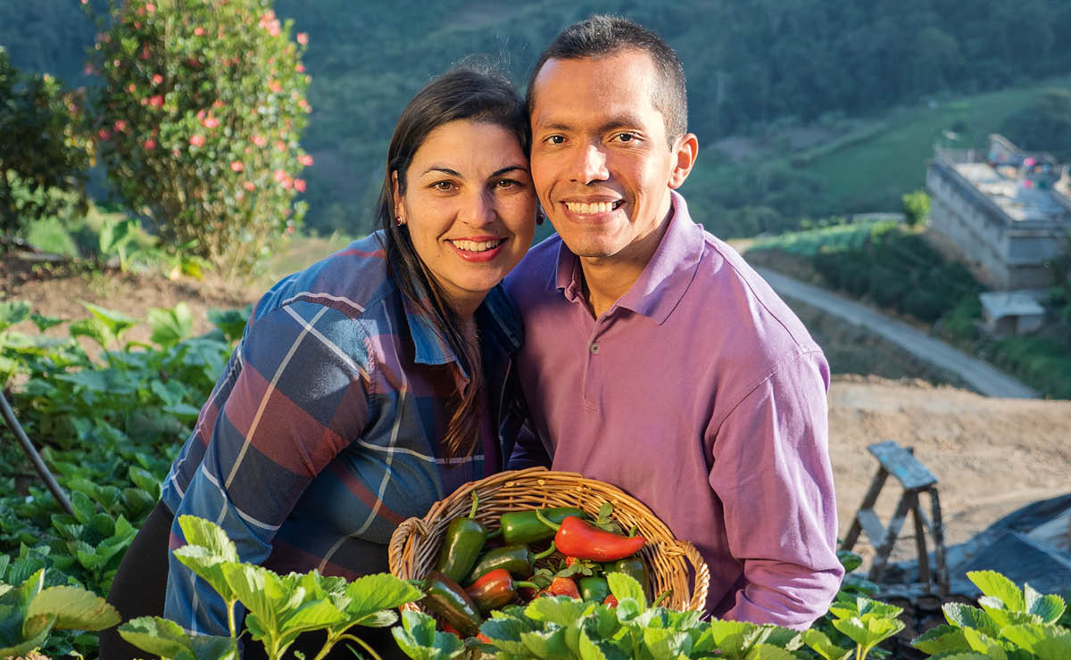 Sambil tersenyum, Carmen dan Edgar menunjukkan cabe yang mereka tanam di kebun mereka.